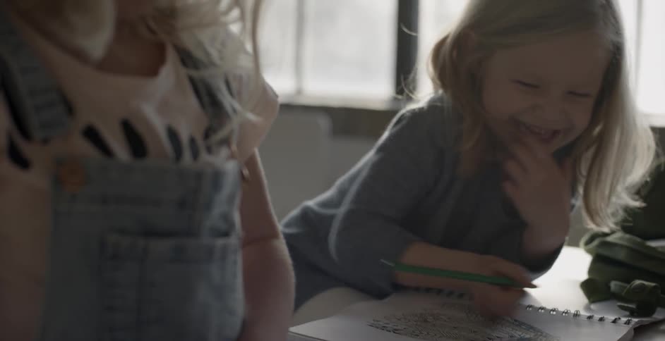 A child smiles as she draws in a book