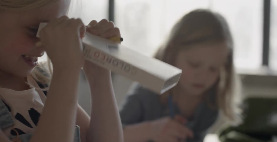 A girl is looking through an empty box of colored pencils