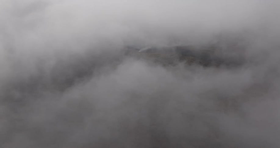 Hills covered in vegetation and trees seen through clouds