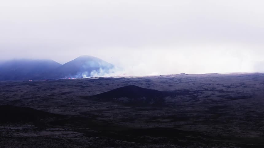 Smoke rises as flaming hot lava flows across the snow covered ground