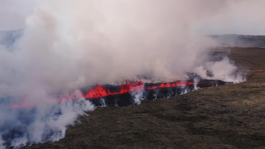 Volcanic fissure line spewing lava and rolling plumes of white smoke