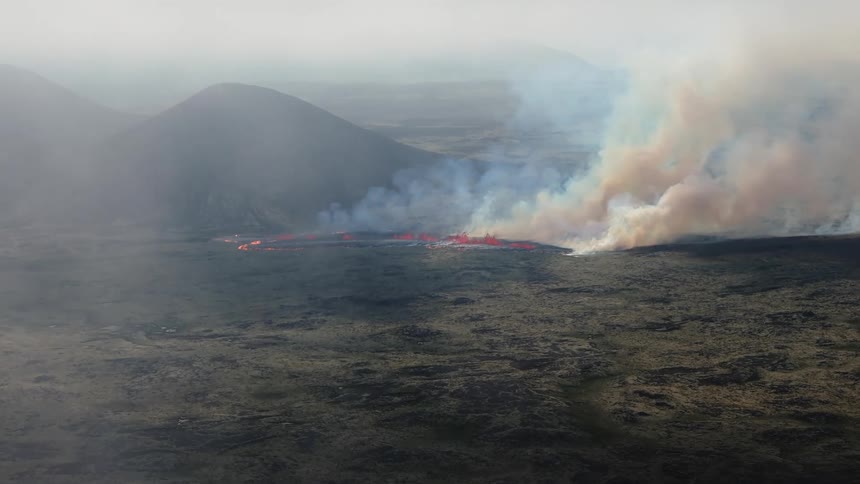 Smoke rises as glowing hot lava flows and splashes across the land