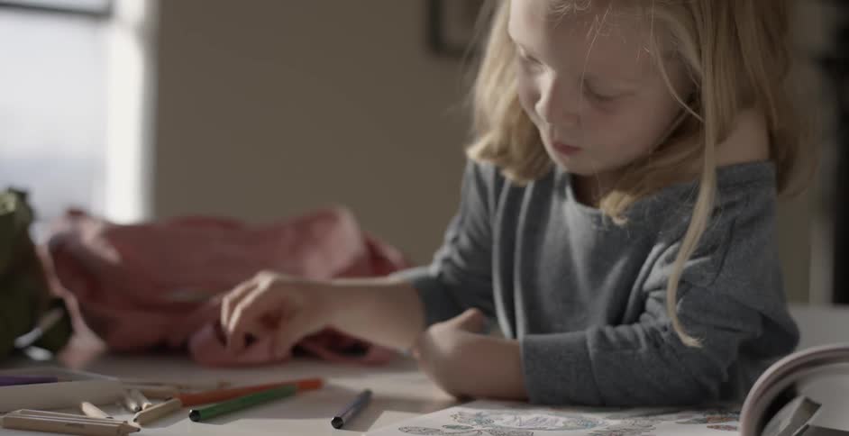 A girl uses colored pencils to draw on paper