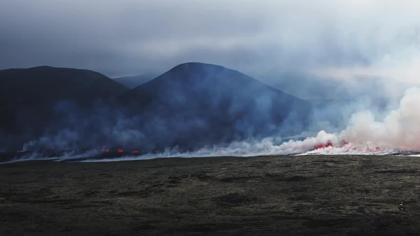 Smoke rises as flaming hot lava flows and splashes across the land