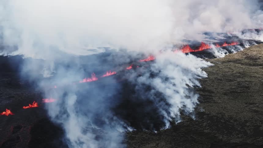 Smoke rolling out of fissure lines with splashing lava
