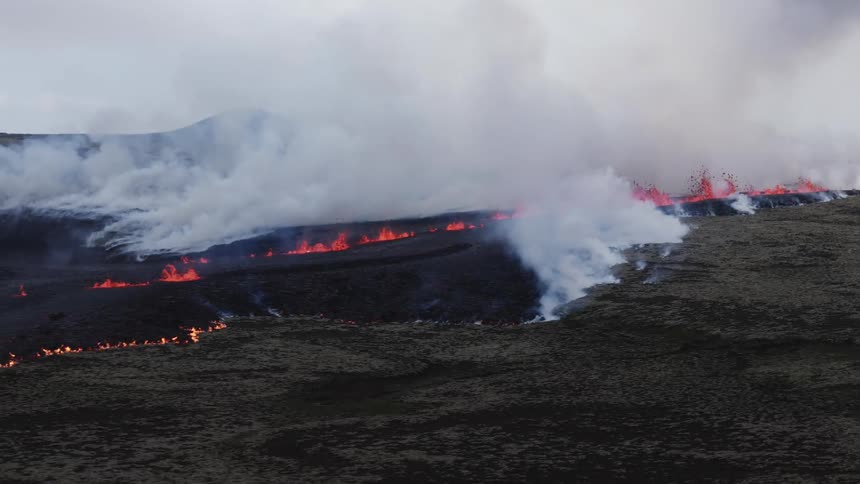 Smoke rises as glowing hot lava splashes as it flows across the land