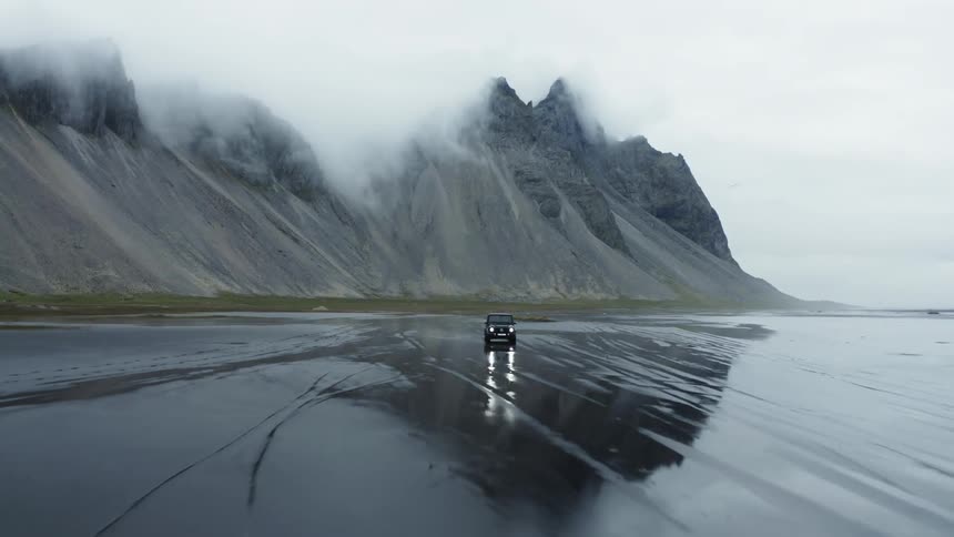 A sports utility vehicle drives on a black beach