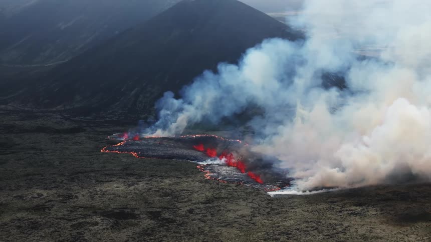 Aerial view of a volcanic eruption next to a mountain