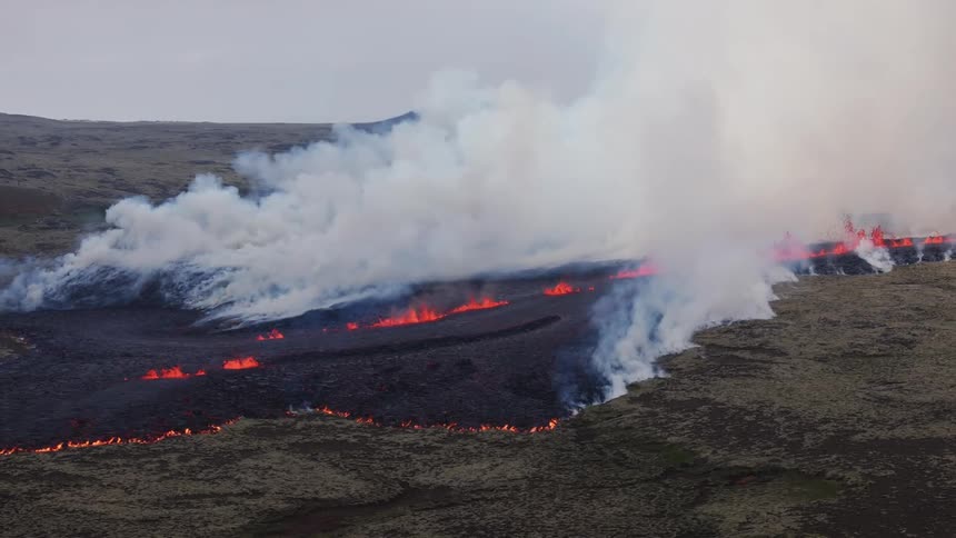 Aerial of thick white smoke and orange lava shooting up from volcanic fissure lines