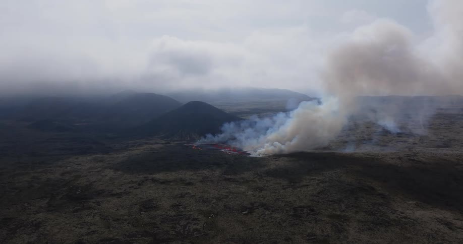 Smoke rises as glowing hot lava from an erupting volcano flows across the land