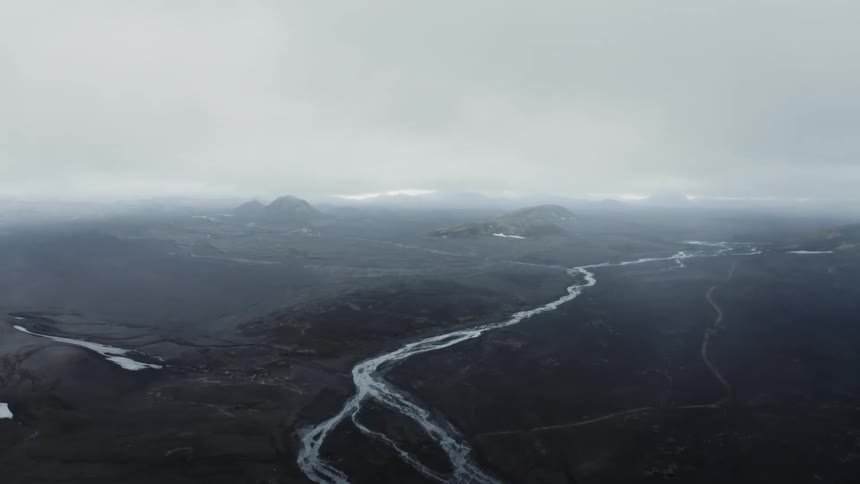 Aerial view of a river basin and some mountains on a cloudy day