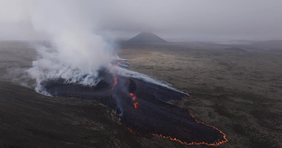Lava smolders at the base of a volcano on a stormy day