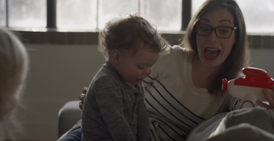 A woman plays with children on a couch