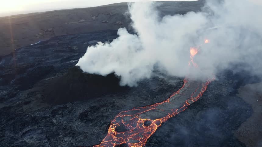Hot glowing lava flows as a volcano erupts and smoke rises