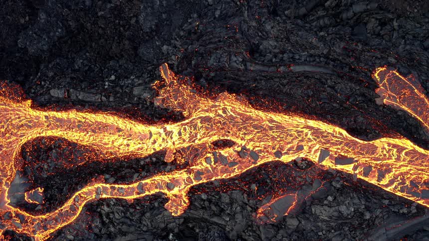 Molten hot lava glows as it flows from an erupting volcano