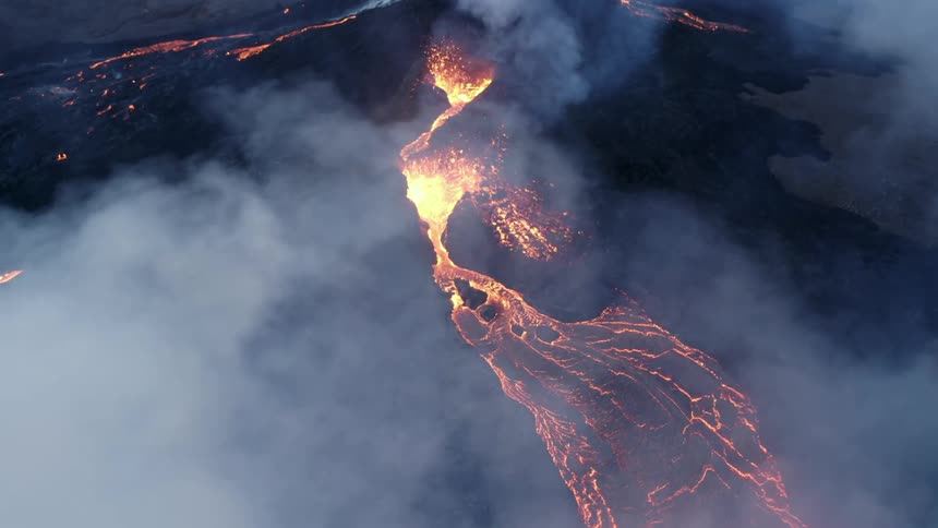From the sky a volcano erupting with billowing smoke and molten lava spewing out