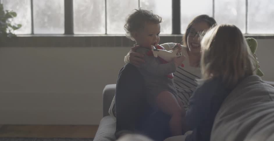 Woman sits on a couch with three children in a sunny room