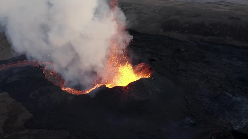 Aerial of an erupting volcano with boiling lava river