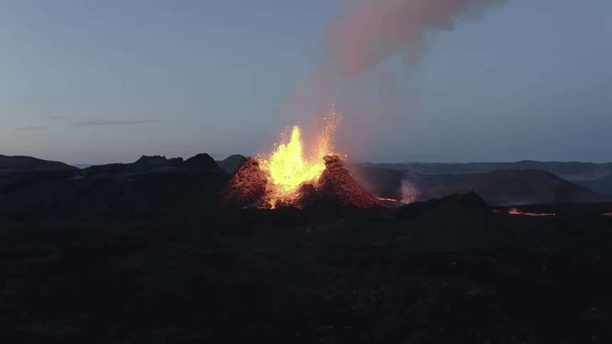 Lava spews from a volcano during eruption then flows down the sides of it