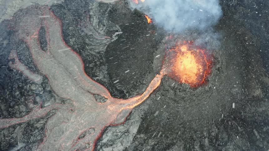 Aerial view of lava flowing from a volcano while its raining
