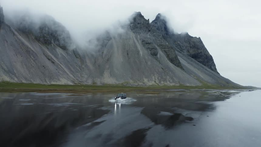 A car moving on a land covered with water near a mountain during the day