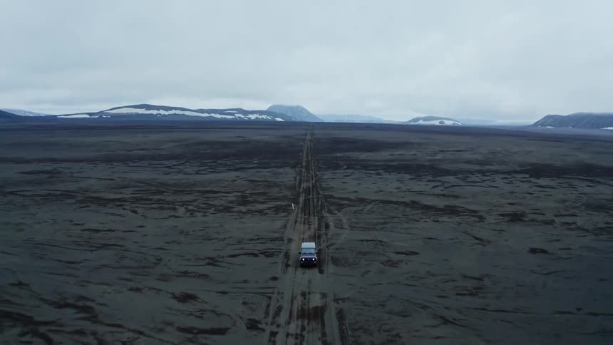 Pickup truck driving on a dirt road in a natural setting with snowcovered mountains in the horizon