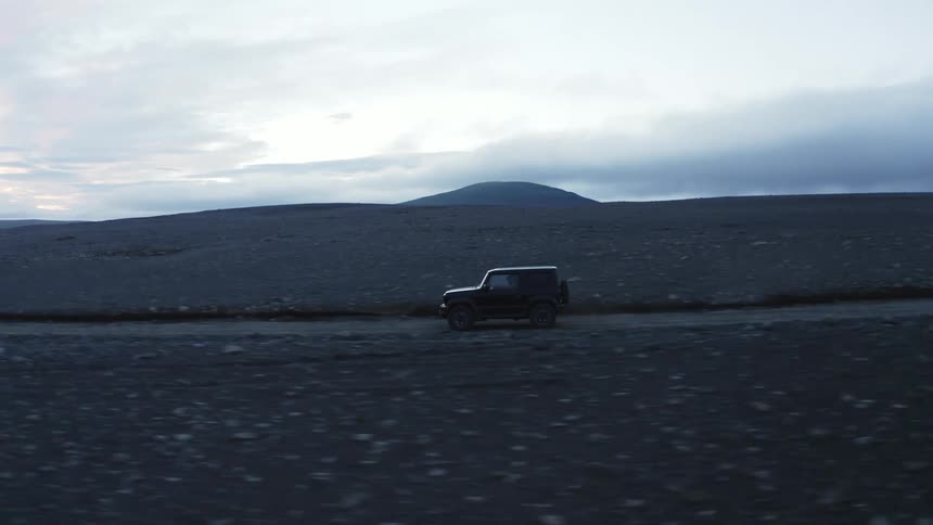 A black jeep driving on a dirt road in the desert