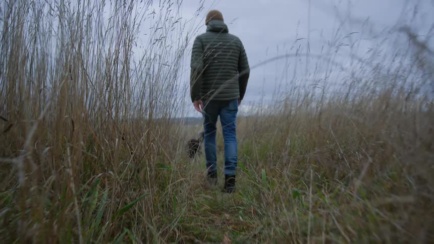 Man walks through the countryside with his dog