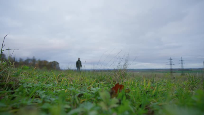Man throwing a ball for his dog to fetch in a pasture on a cloudy day