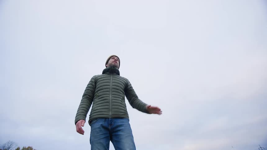 Man throws ball for dog then calls it back while standing near autumnal forest