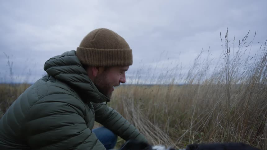 Man pets his dog while walking in the countryside
