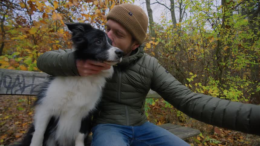 A man taking a photo with his dog in a park