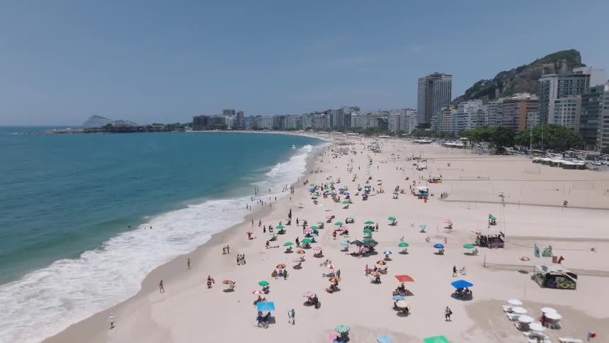 A crowd of people visit the beach in a resort area on a sunny day