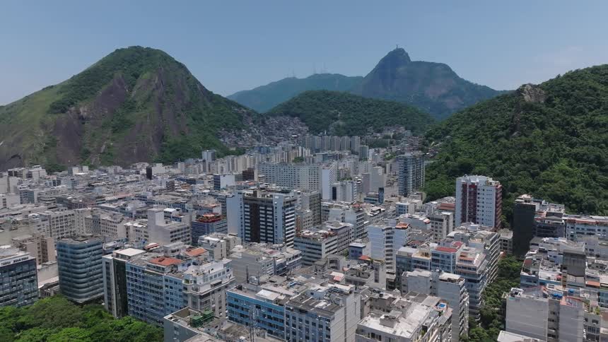 Aerial view of buildings in rio de janeiro surrounded by hills covered in trees on a sunny day