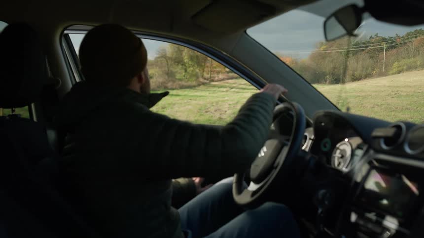 A man getting out of a car parked on a road in the plains