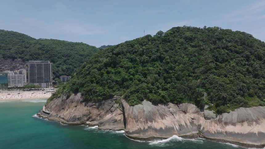 Large forested mountains border seaside city with busy beach