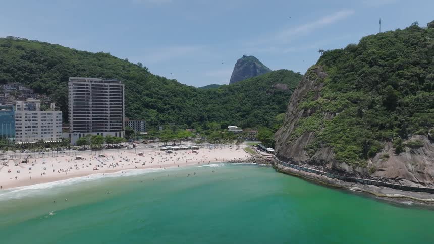 Aerial of people walking on the beach in a lush resort area