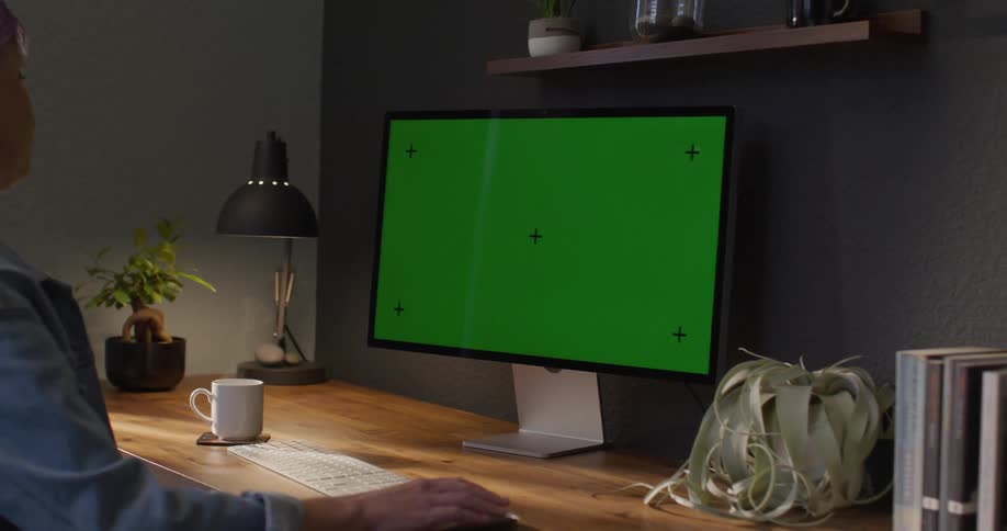 Woman working on a computer with a green replaceable screen