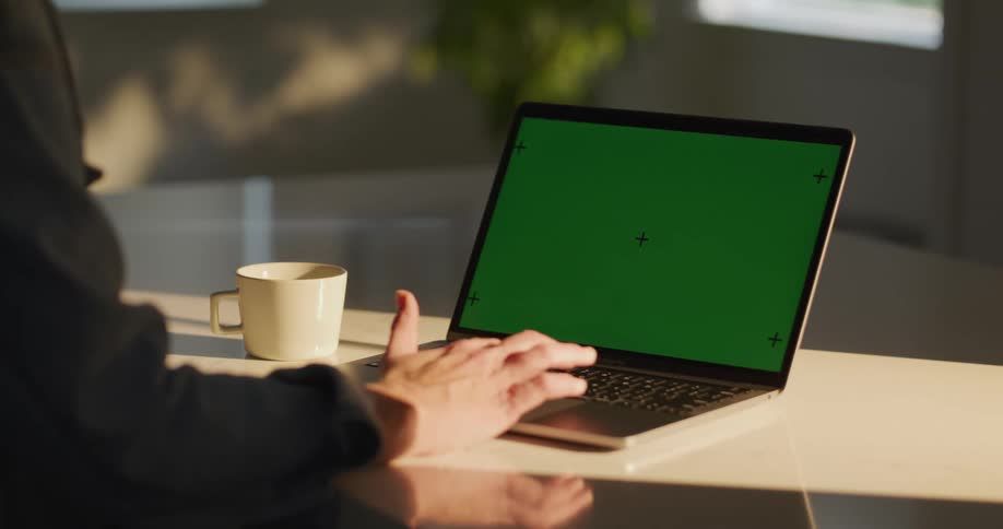 An adult scrolls on a laptop while sitting at an office workspace