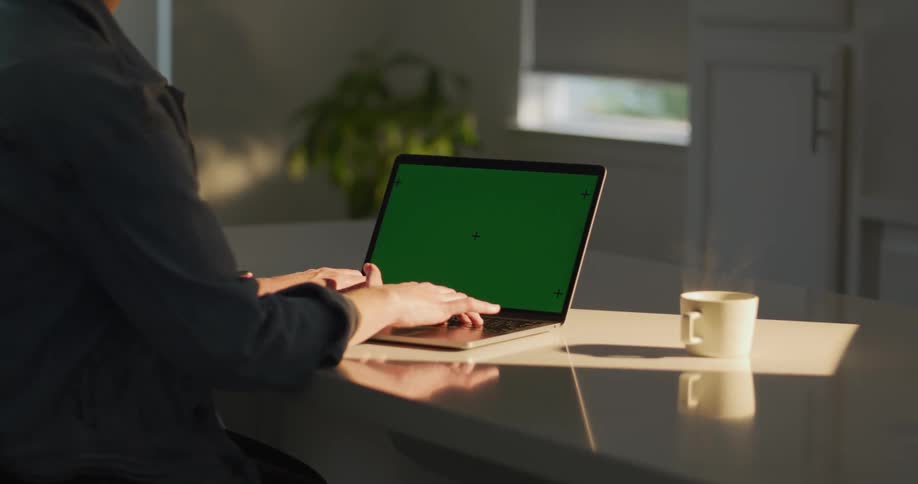 An adult types on a laptop at a desk