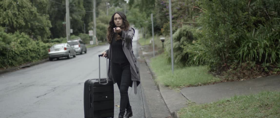 A woman rolls her bag onto the street