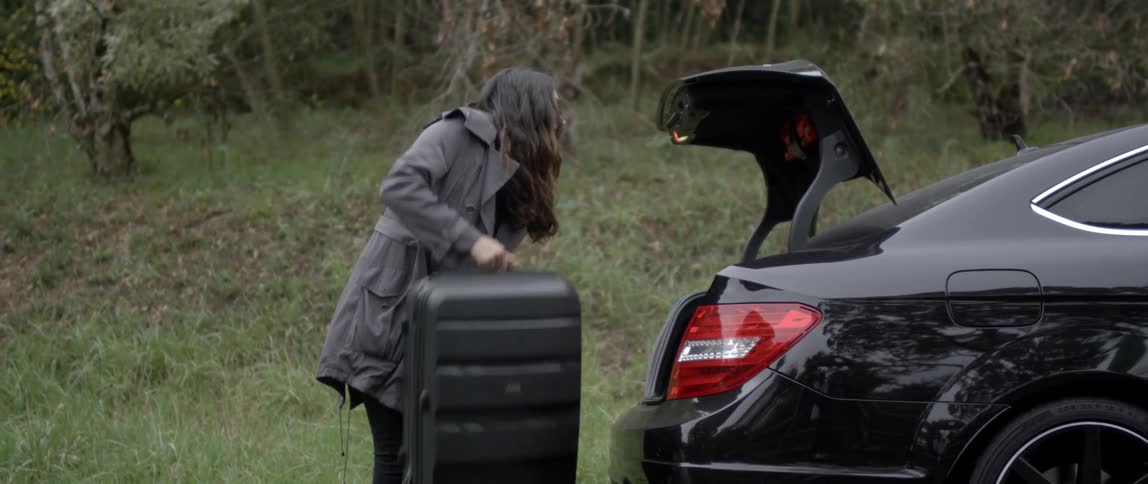 Woman loads a suitcase into the trunk of a car
