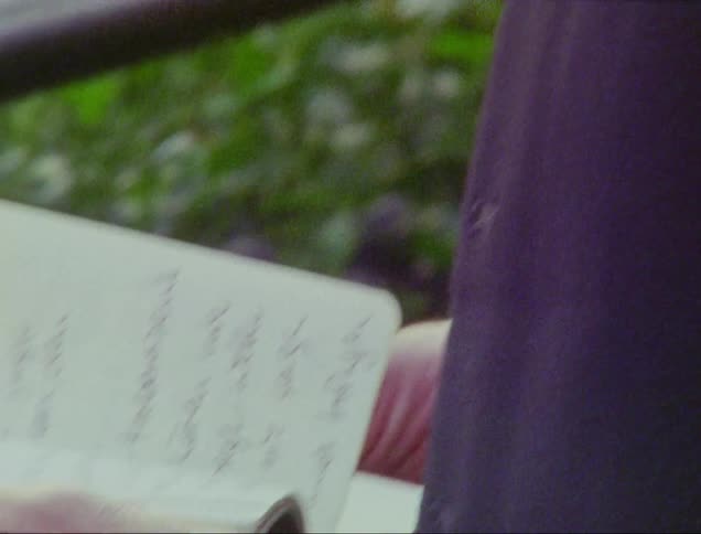 Man with beard and gray shirt turns over notebook pages with handwritten text
