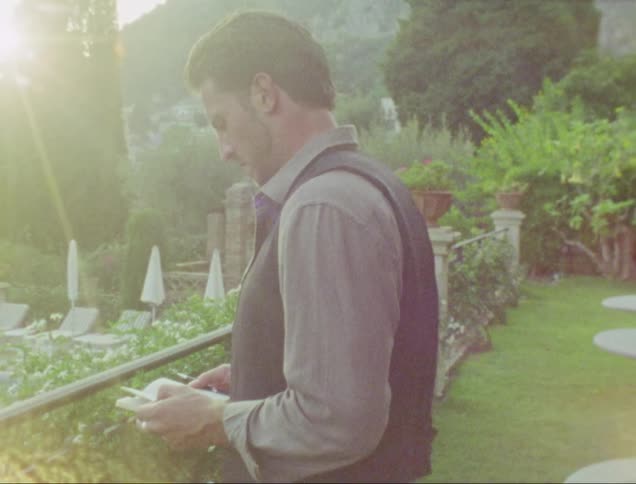 Video footage of a man outdoors in a garden at dusk