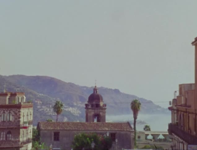 A tower with palm trees on both sides overlooking the hilly coast