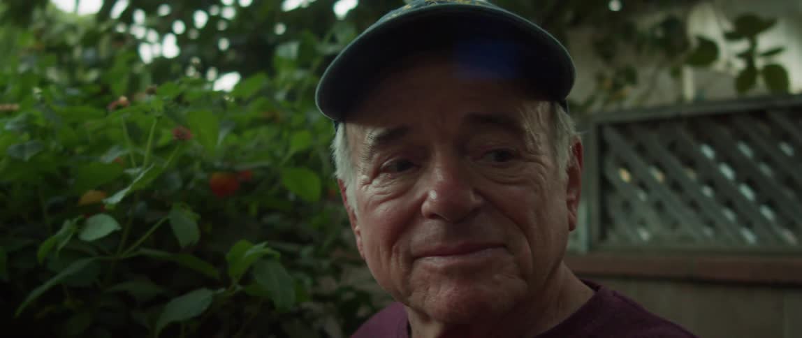 Portrait of an elderly person wearing a cap with a facial expression of joyful excitement