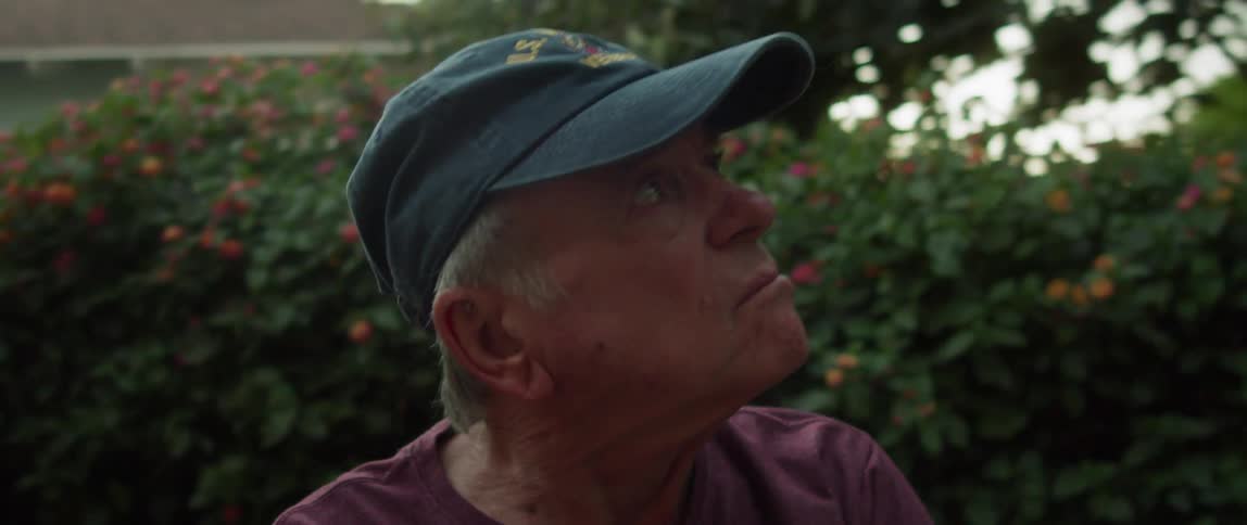 Portrait of an elderly man sitting in the backyard looking up at the trees