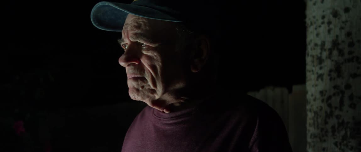 Portrait of an elderly person with a cap at night with a facial expression of sadness