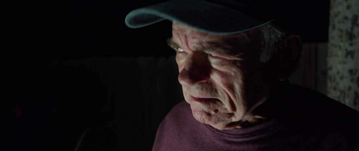 Portrait of an elderly person with a cap in the dark at night