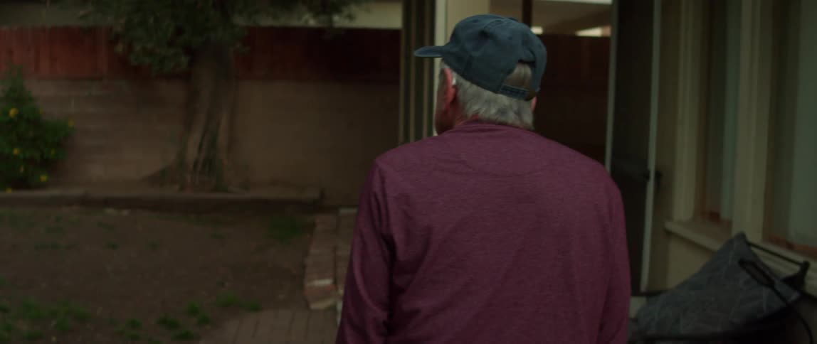 Elderly person walking in the backyard with their back turned observing